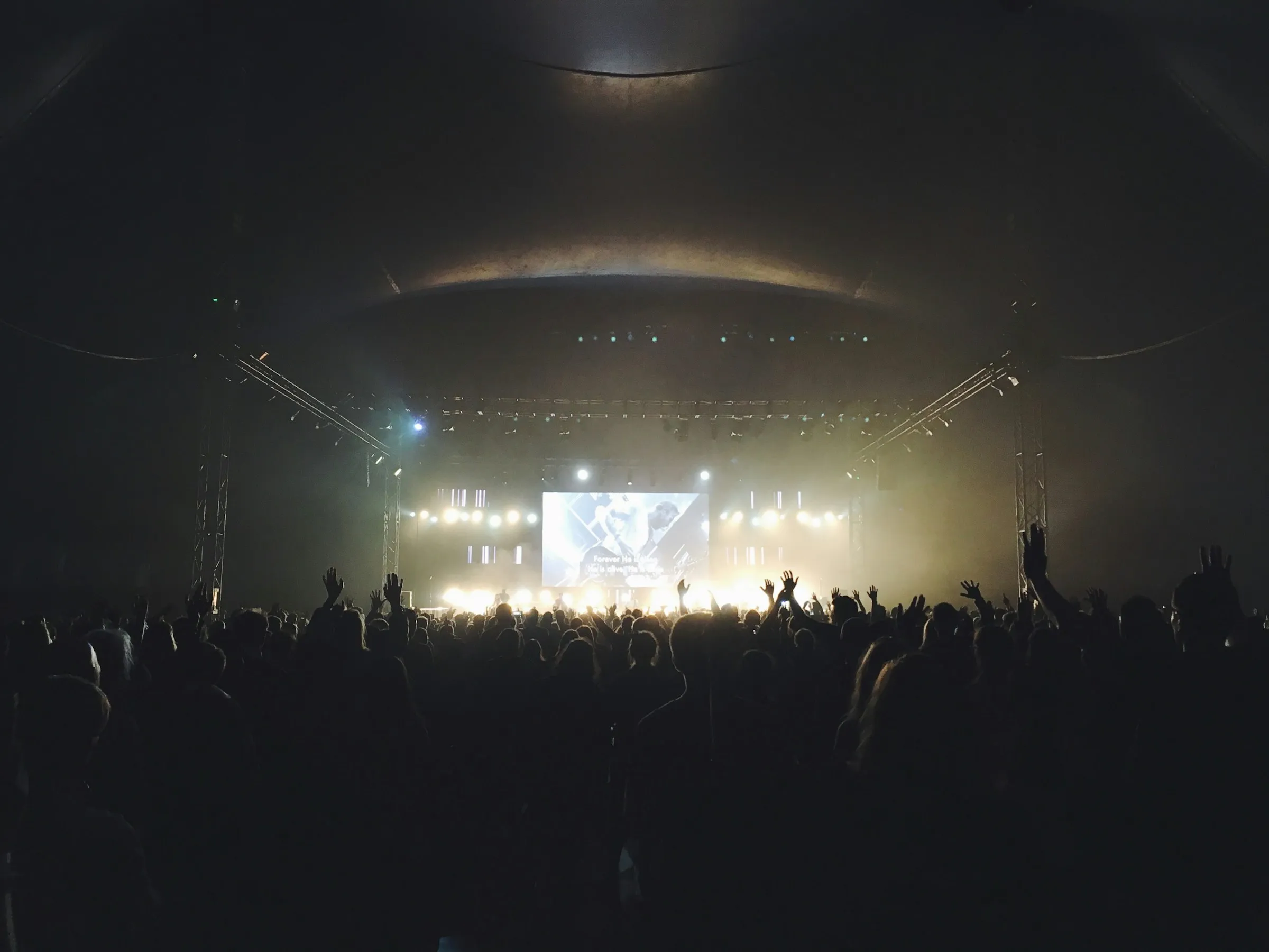 Festival stage under light beams with crowd silhouettes